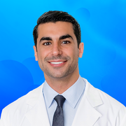 A smiling man in a white coat and tie, representing professional expertise, relevant to WeNatal's prenatal wellness and vitamin supplement offerings.